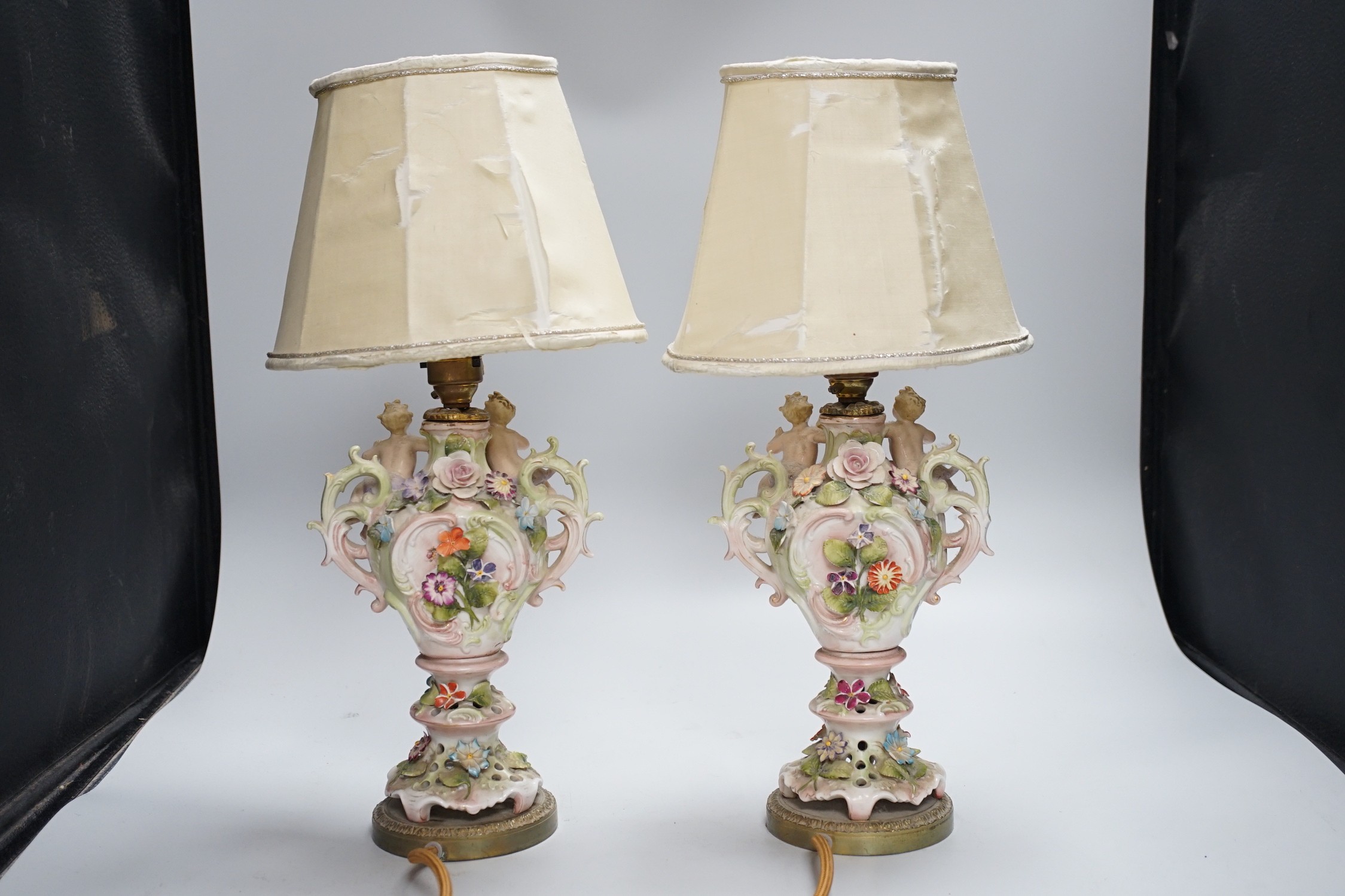 A pair of German porcelain flower encrusted lamps, height 24cm